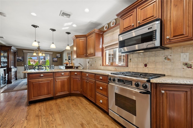 kitchen featuring pendant lighting, a peninsula, appliances with stainless steel finishes, and brown cabinets