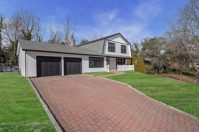 dutch colonial with decorative driveway, covered porch, a gambrel roof, an attached garage, and a front yard