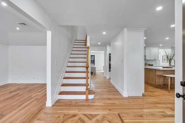 staircase featuring recessed lighting, visible vents, baseboards, and wood finished floors