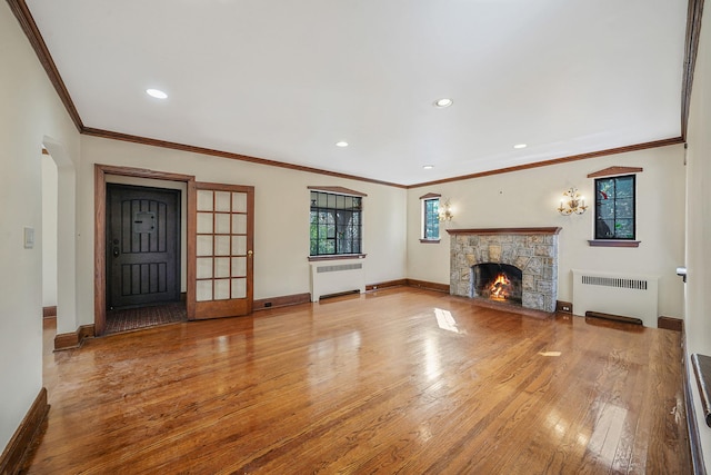 unfurnished living room with radiator, a fireplace, baseboards, and wood finished floors