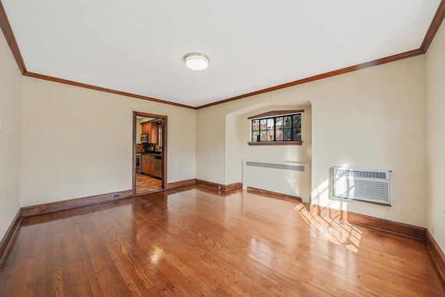 182-37 Radnor Rd, Jamaica Estates, NY 11432 - unfurnished living room featuring wood finished floors, baseboards, radiator, a wall mounted air conditioner, and crown molding