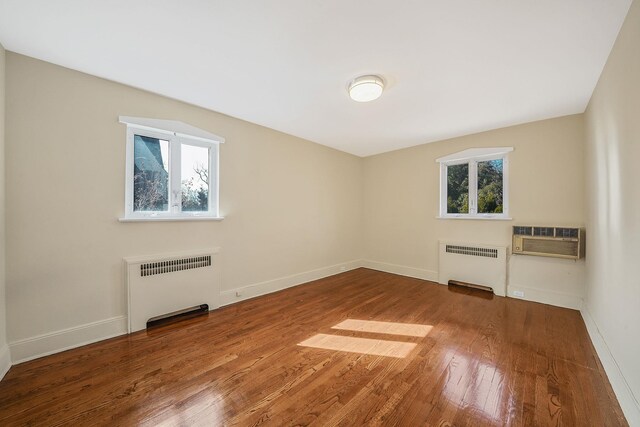 182-37 Radnor Rd, Jamaica Estates, NY 11432 - empty room with radiator, a wall unit AC, baseboards, and hardwood / wood-style floors