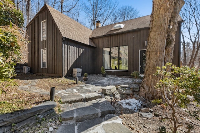 view of property exterior with roof with shingles and a chimney