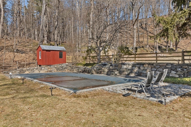 view of yard featuring a storage unit, an outdoor structure, and fence