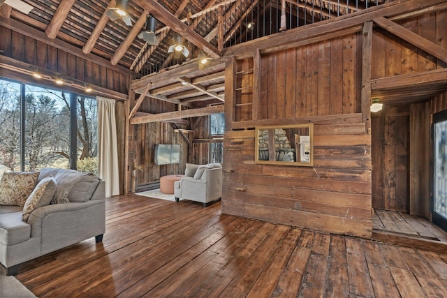 unfurnished living room with wood-type flooring, high vaulted ceiling, and wood walls