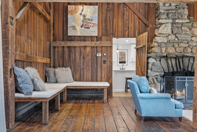 living area with hardwood / wood-style floors, a fireplace, and wood walls