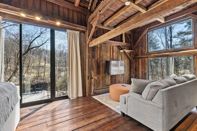 living room featuring hardwood / wood-style flooring, wooden walls, a wealth of natural light, and a baseboard radiator