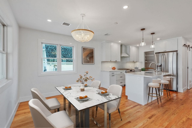 kitchen featuring white cabinets, an island with sink, decorative light fixtures, light countertops, and stainless steel refrigerator with ice dispenser