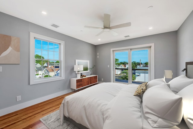 bedroom featuring wood finished floors, visible vents, baseboards, and multiple windows