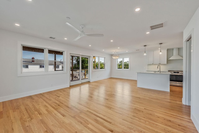 unfurnished living room with light wood-type flooring, baseboards, visible vents, and a sink