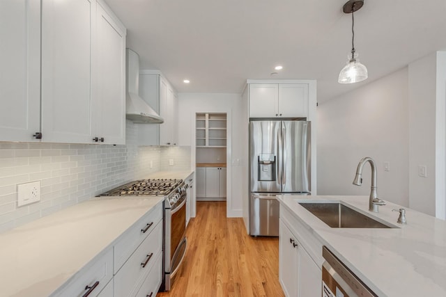 kitchen with decorative backsplash, wall chimney exhaust hood, appliances with stainless steel finishes, white cabinetry, and a sink