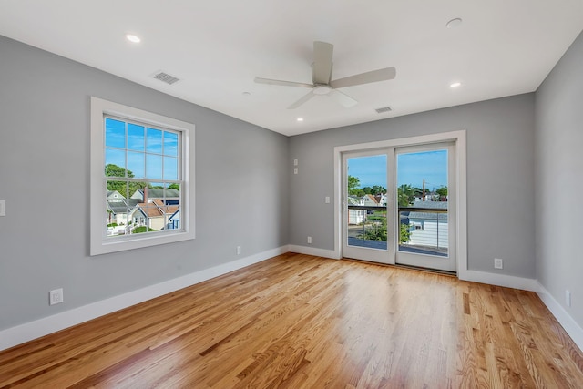 empty room featuring light wood-type flooring, plenty of natural light, visible vents, and baseboards