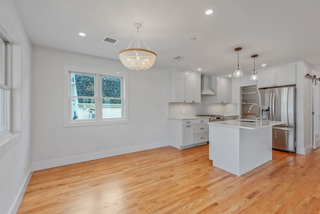 kitchen featuring white cabinetry, light countertops, stainless steel fridge with ice dispenser, an island with sink, and pendant lighting