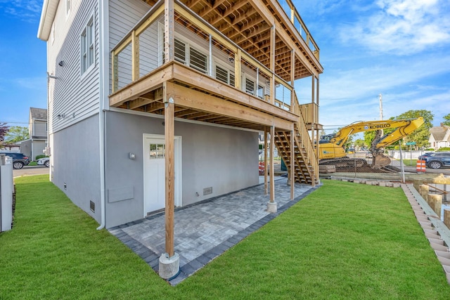 back of house featuring stairway, a deck, a lawn, and a patio