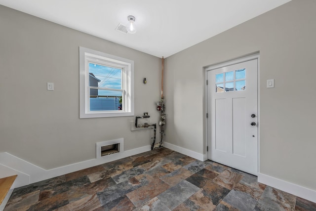 foyer with stone finish flooring, plenty of natural light, and baseboards