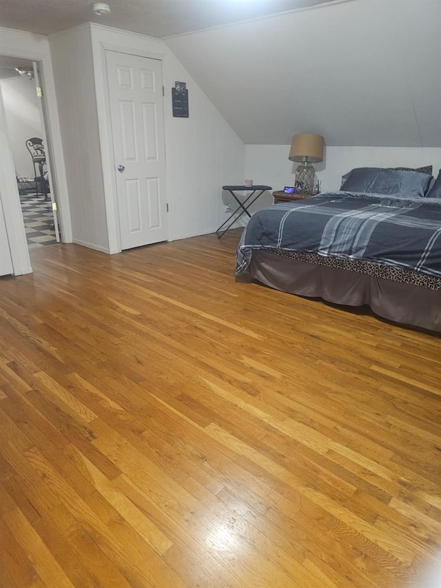 bedroom featuring light wood finished floors and vaulted ceiling