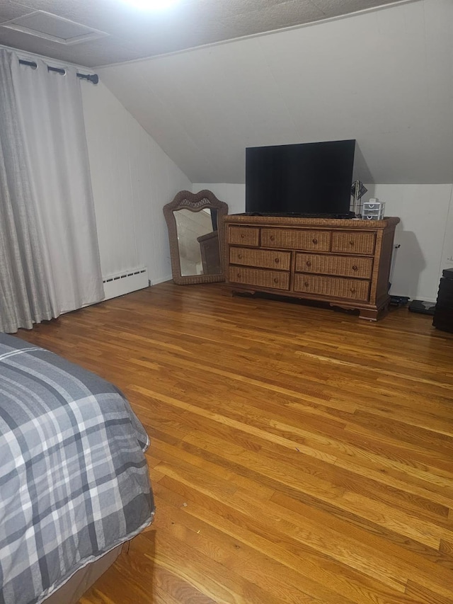 bedroom featuring light wood-style floors, a baseboard radiator, and lofted ceiling