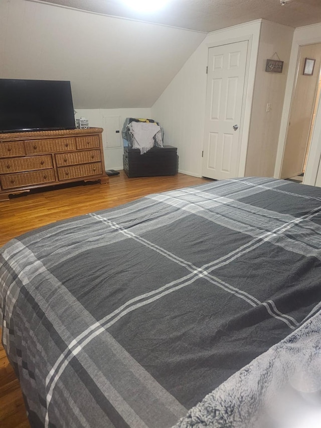 bedroom with vaulted ceiling and wood finished floors