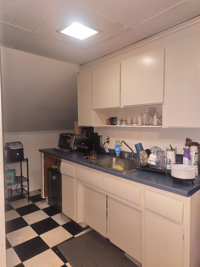 kitchen featuring dark countertops, white cabinets, a sink, and light floors