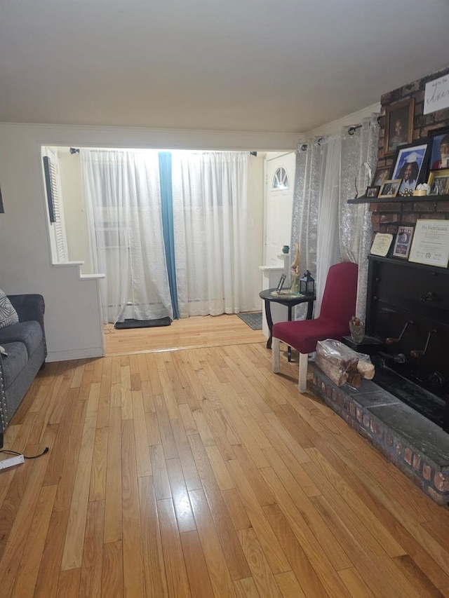 living area with a brick fireplace and wood-type flooring