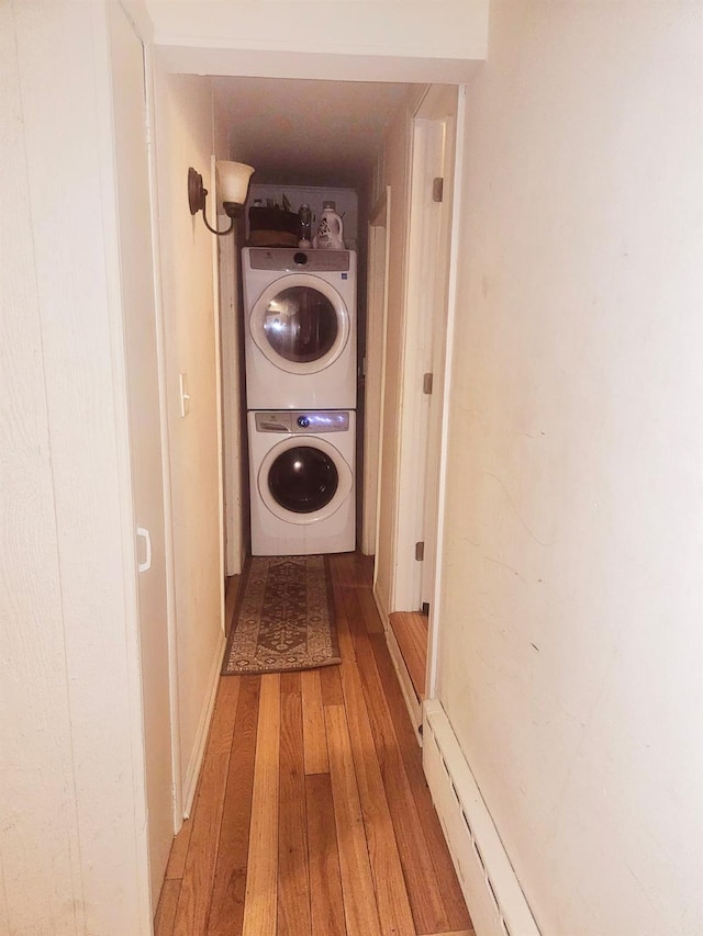 laundry room with stacked washer / drying machine, laundry area, and wood-type flooring