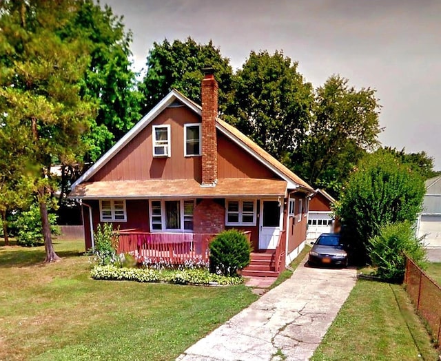 view of front facade with a chimney, covered porch, concrete driveway, and a front lawn