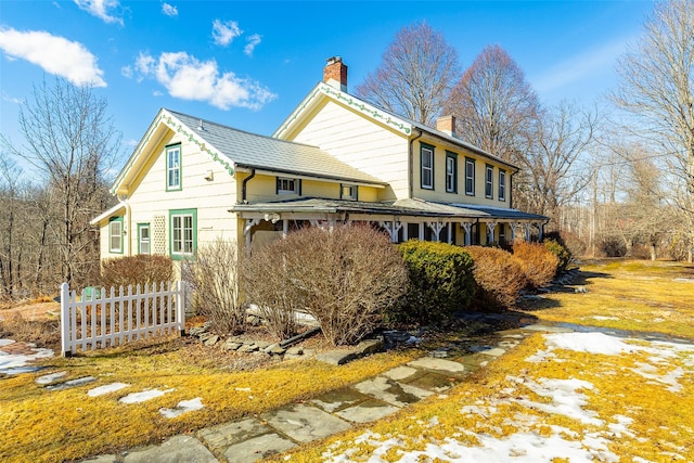 view of side of home with a chimney and fence