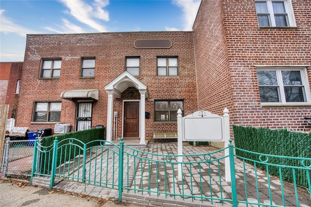 view of property with a fenced front yard, a gate, and brick siding