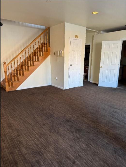 unfurnished living room with carpet, stairs, and baseboards