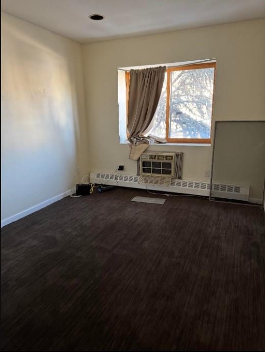 empty room with baseboards, dark wood-type flooring, and a wall mounted air conditioner