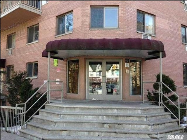 property entrance featuring french doors and brick siding