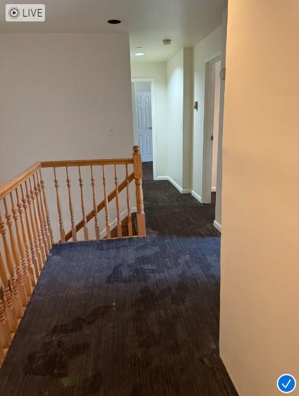 corridor with baseboards, wood finished floors, and an upstairs landing