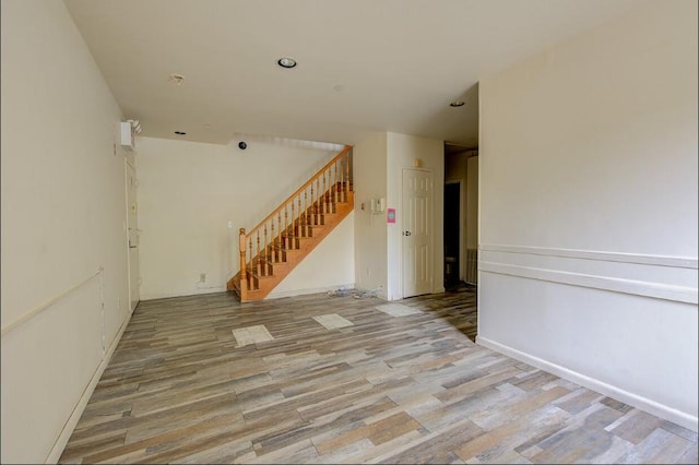 empty room featuring recessed lighting, light wood-style flooring, and stairs