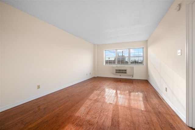 unfurnished room featuring heating unit, hardwood / wood-style flooring, and baseboards