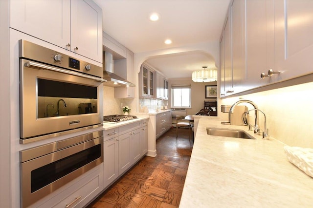 kitchen with a sink, tasteful backsplash, recessed lighting, stainless steel appliances, and wall chimney range hood