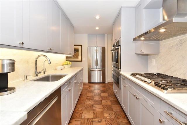 kitchen with backsplash, stainless steel appliances, wall chimney exhaust hood, and a sink