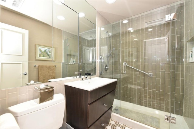 full bathroom featuring vanity, a shower stall, toilet, and visible vents