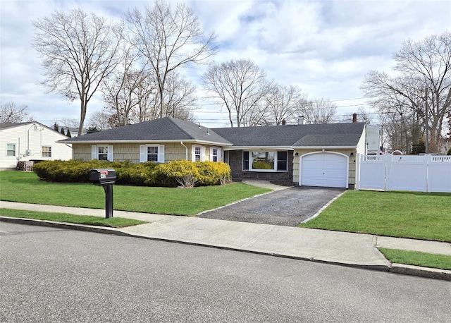 view of front of house with aphalt driveway, an attached garage, a gate, fence, and a front lawn