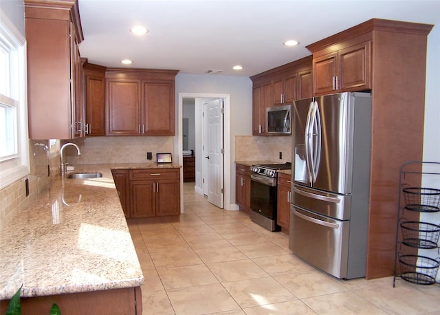 kitchen featuring tasteful backsplash, visible vents, light stone counters, stainless steel appliances, and a sink