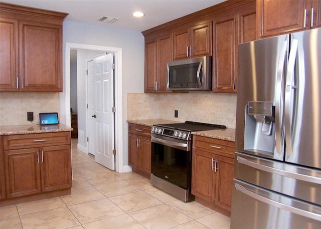 kitchen featuring appliances with stainless steel finishes, visible vents, and light stone counters