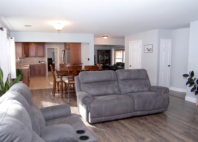 living area with light wood-type flooring, visible vents, and baseboards