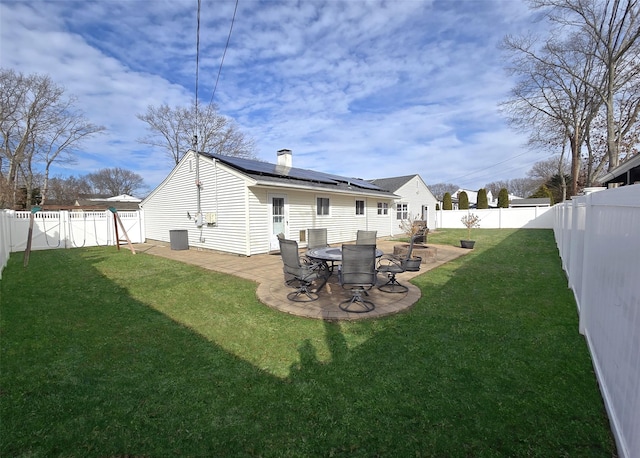 rear view of property with a fenced backyard, solar panels, central AC, a yard, and a patio area