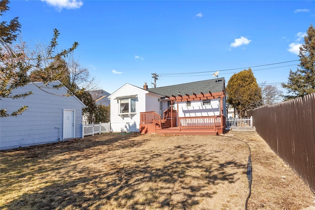 back of property featuring a fenced backyard, a deck, a shingled roof, and a yard