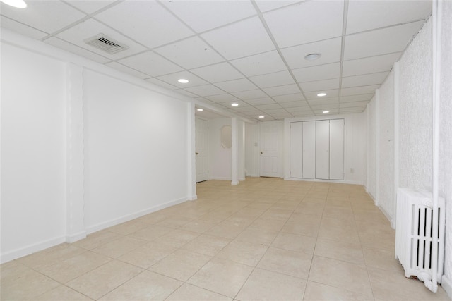 finished basement featuring radiator heating unit, visible vents, a drop ceiling, and recessed lighting