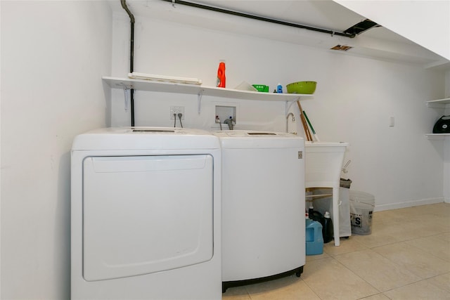 clothes washing area with laundry area, light tile patterned flooring, washer and clothes dryer, and baseboards