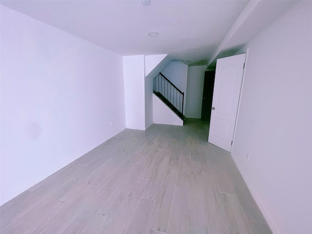 spare room featuring light wood-type flooring and stairway