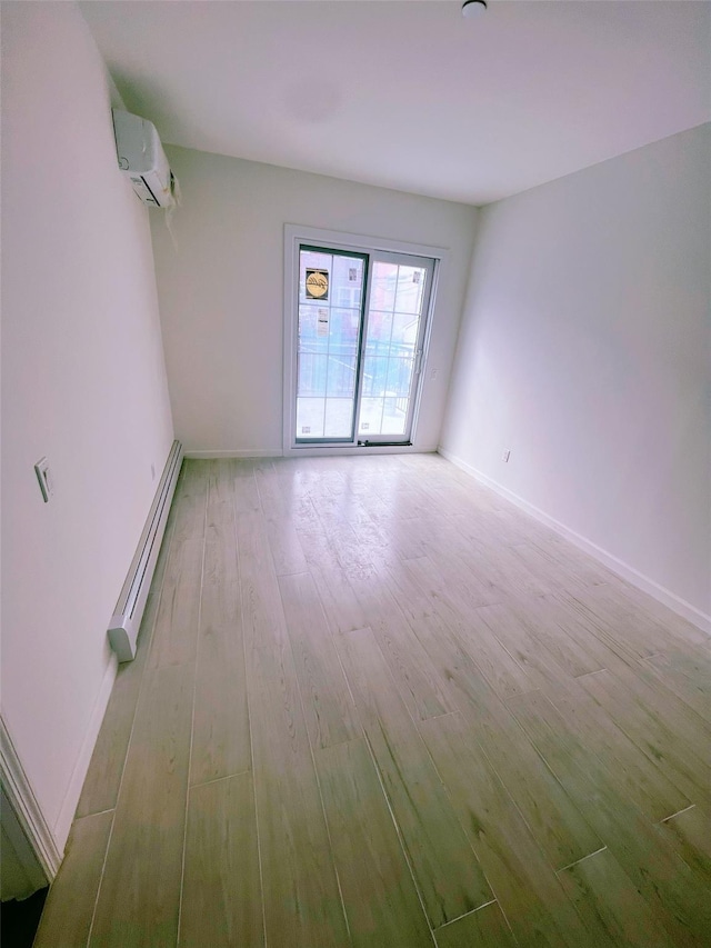 empty room featuring baseboards, baseboard heating, light wood-type flooring, and a wall mounted air conditioner