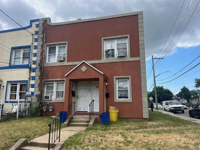 townhome / multi-family property featuring a front lawn, cooling unit, and stucco siding