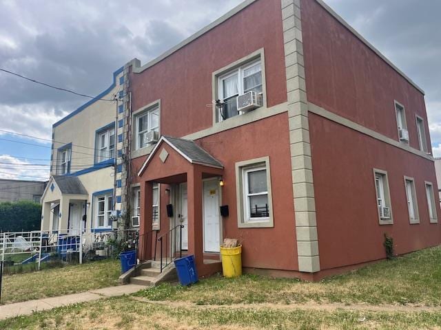 view of front of house with a front yard, cooling unit, and stucco siding