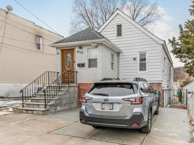 bungalow with a shingled roof, brick siding, and driveway